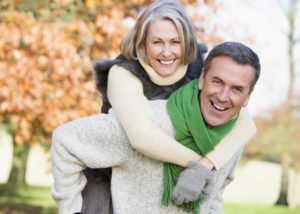 Middle aged couple outside in the Fall. Husband gives wife a piggyback ride